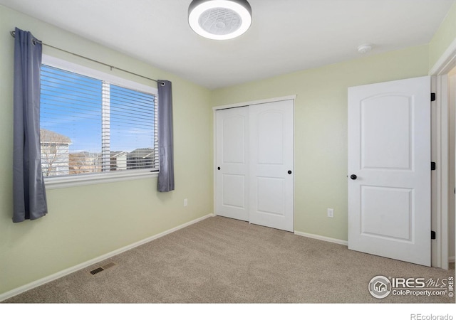 unfurnished bedroom featuring visible vents, carpet floors, baseboards, and a closet