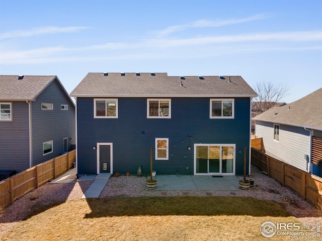 back of property with a patio area, a lawn, a shingled roof, and a fenced backyard