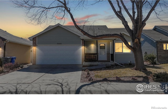 view of front of home with brick siding, an attached garage, and driveway