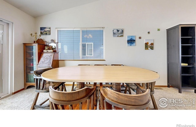 dining area with baseboards, light colored carpet, and vaulted ceiling