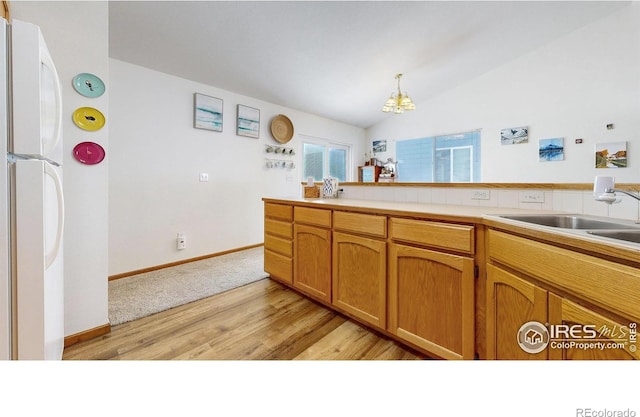 kitchen with light wood-style flooring, freestanding refrigerator, light countertops, a chandelier, and vaulted ceiling