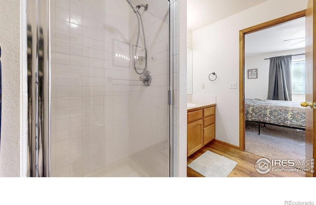 ensuite bathroom featuring wood finished floors, vanity, ensuite bath, and a shower stall