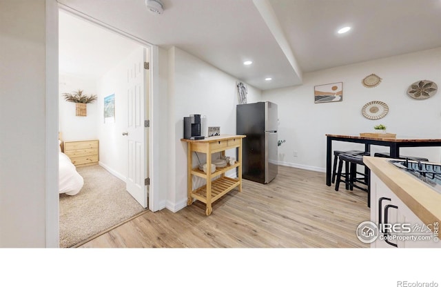 interior space featuring baseboards, light wood finished floors, recessed lighting, freestanding refrigerator, and light countertops