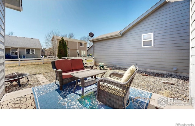 view of patio with an outdoor living space with a fire pit and fence