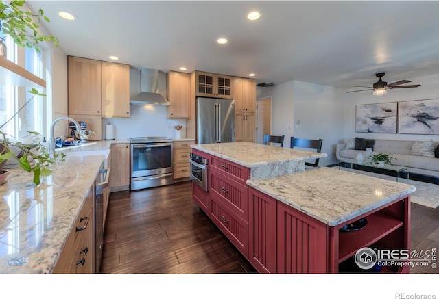 kitchen with dark wood-style floors, a kitchen island, recessed lighting, appliances with stainless steel finishes, and wall chimney range hood