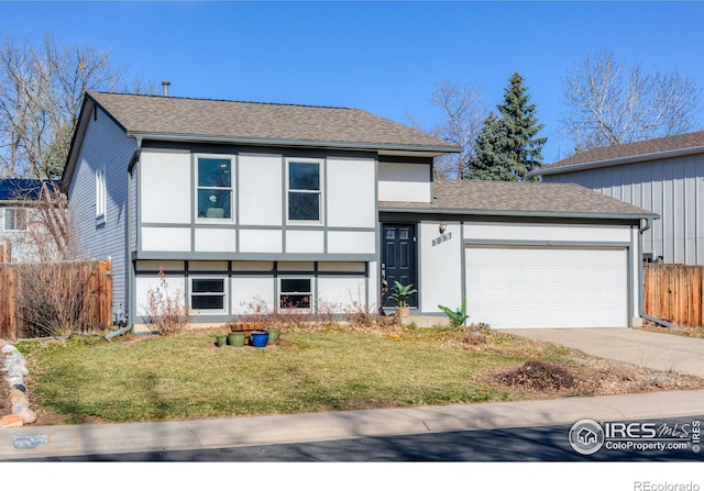 tri-level home featuring a front yard, fence, driveway, stucco siding, and a garage