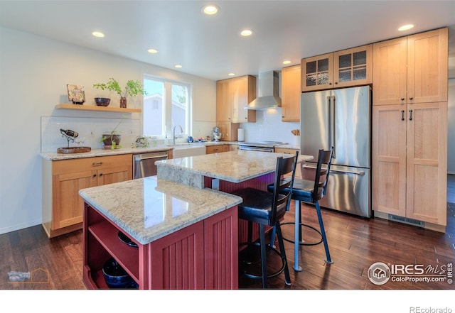 kitchen with appliances with stainless steel finishes, a kitchen island, wall chimney exhaust hood, and open shelves