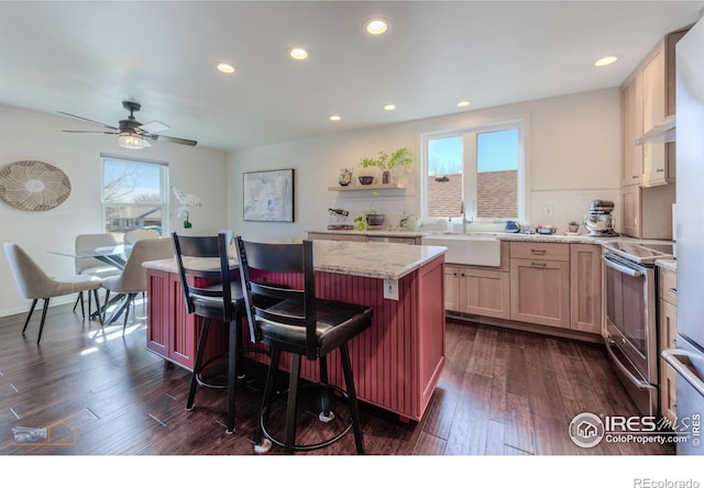 kitchen with stainless steel electric range oven, a center island, a wealth of natural light, and a sink