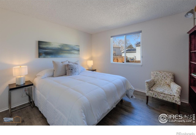 bedroom with baseboards, a textured ceiling, and wood finished floors