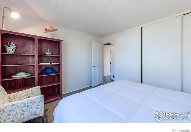 bedroom with a closet, a textured ceiling, and wood finished floors