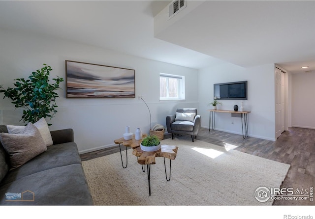 living room featuring visible vents, baseboards, and wood finished floors