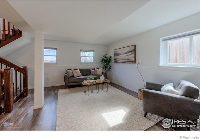 living room with dark wood-type flooring, stairway, and baseboards