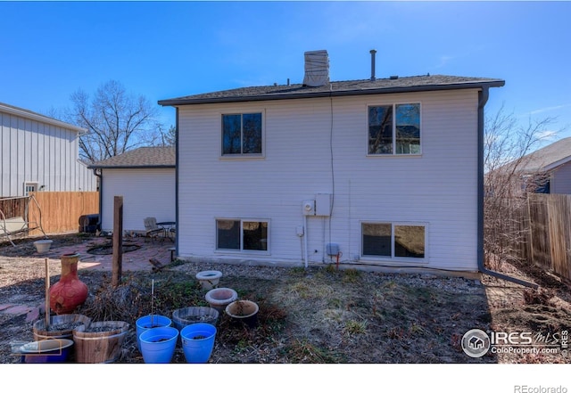 rear view of property featuring a patio area, fence, roof with shingles, and a chimney