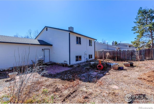 rear view of property featuring a chimney and fence