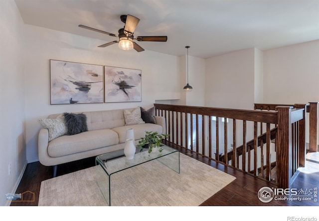 living area with baseboards, a ceiling fan, and wood finished floors