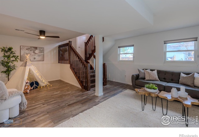 living room with a ceiling fan, baseboards, wood finished floors, visible vents, and stairway