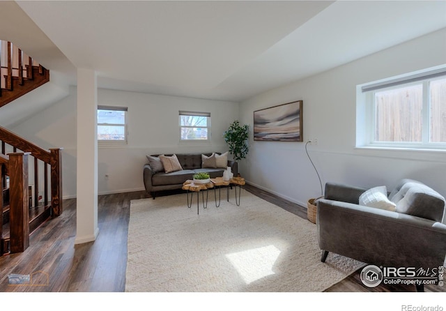 living room with stairway, baseboards, and dark wood-style floors