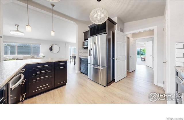 kitchen with decorative light fixtures, tasteful backsplash, light wood-type flooring, and stainless steel appliances