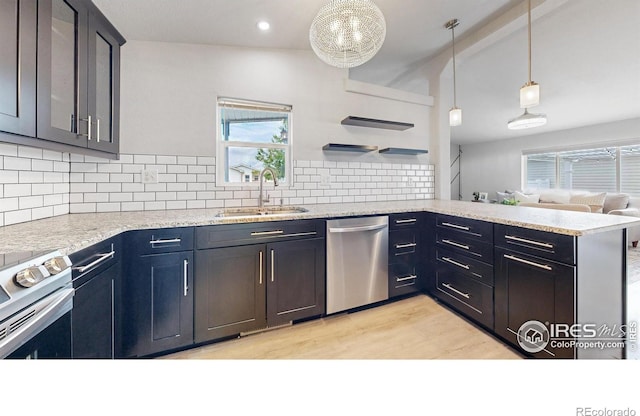 kitchen with light wood finished floors, a peninsula, a sink, decorative backsplash, and stainless steel appliances