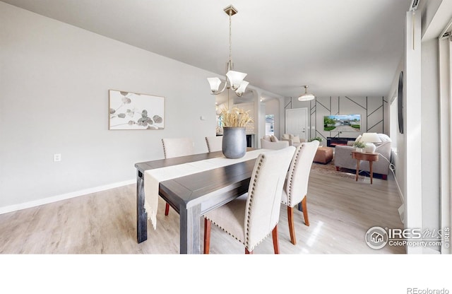 dining area featuring baseboards, light wood-style floors, and a chandelier