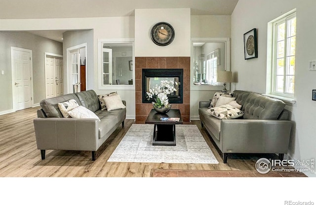 living area featuring a fireplace, wood finished floors, and baseboards