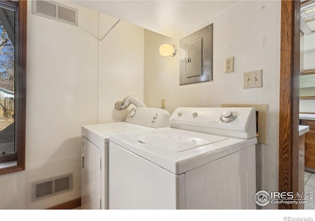 clothes washing area featuring electric panel, visible vents, and washing machine and dryer