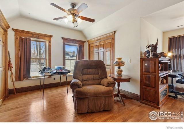 living area with light wood-type flooring, baseboards, ceiling fan, and vaulted ceiling