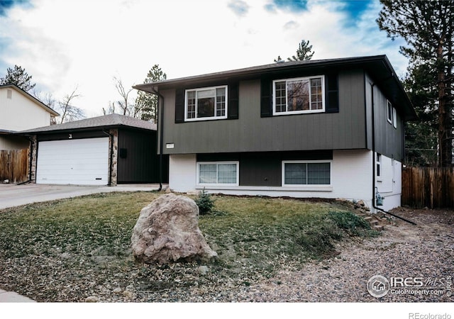 split level home with a front yard, an attached garage, and fence