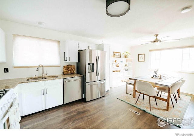 kitchen featuring visible vents, wood finished floors, white cabinets, stainless steel appliances, and a sink