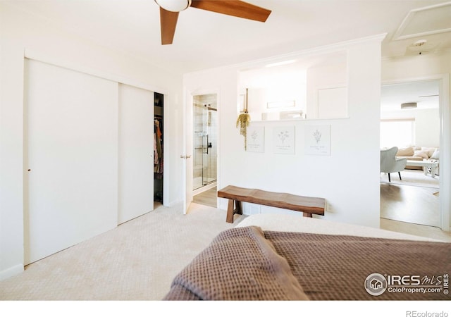 carpeted bedroom featuring ensuite bath, a ceiling fan, and a closet