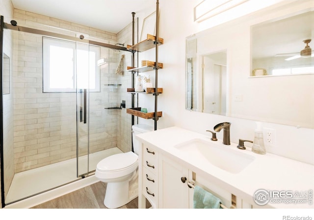 full bath with vanity, wood finished floors, ceiling fan, a shower stall, and toilet