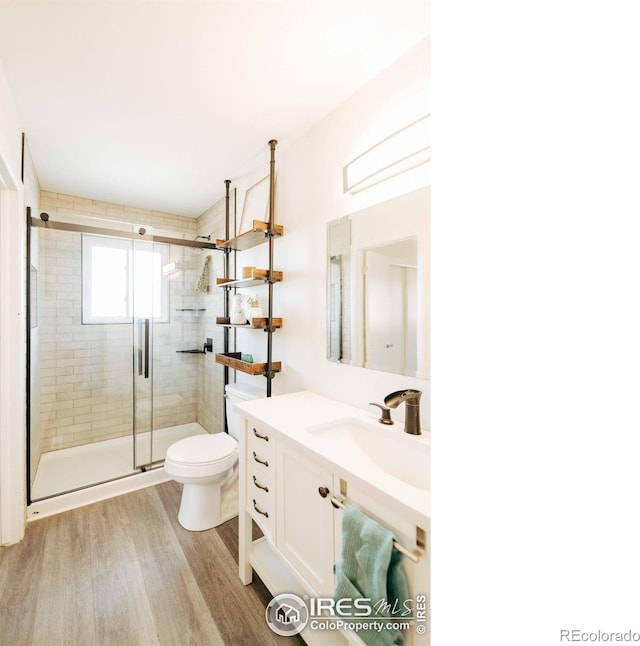 bathroom featuring vanity, toilet, wood finished floors, and a shower stall