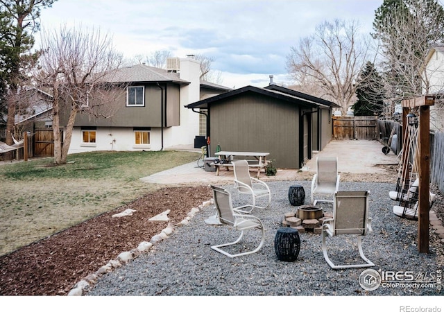 back of house featuring a chimney, a patio, an outdoor fire pit, and a fenced backyard