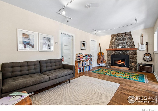 living room featuring a fireplace, rail lighting, and wood finished floors