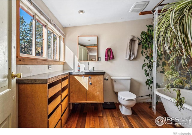 full bath with a freestanding tub, visible vents, toilet, wood finished floors, and vanity