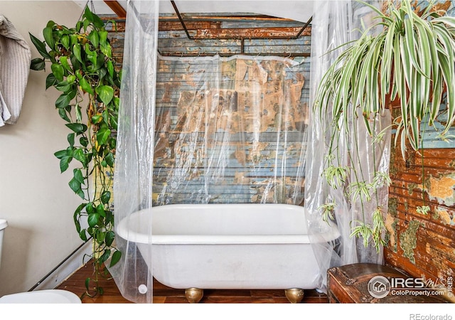 bathroom with toilet and a freestanding tub