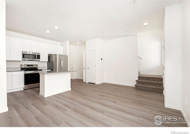 kitchen with baseboards, light wood-type flooring, recessed lighting, white cabinets, and stainless steel appliances