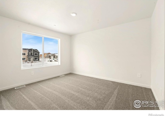 empty room featuring carpet, visible vents, and baseboards