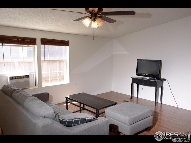 living room featuring a textured ceiling, cooling unit, wood finished floors, and ceiling fan