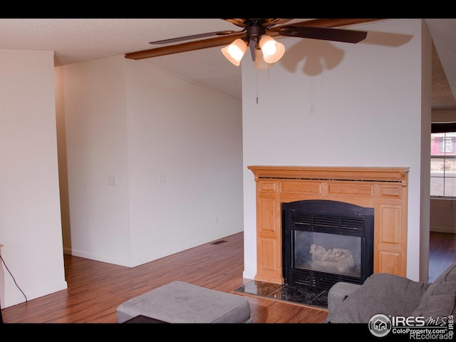 unfurnished living room featuring a ceiling fan, lofted ceiling, a fireplace with flush hearth, and wood finished floors