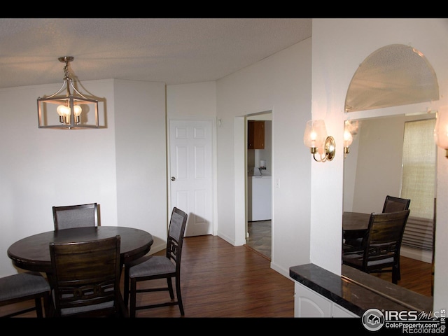 dining space with dark wood finished floors and an inviting chandelier