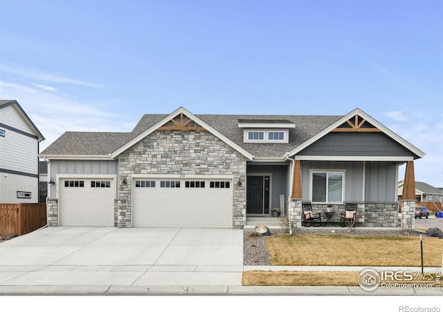 craftsman inspired home with roof with shingles, an attached garage, concrete driveway, stone siding, and board and batten siding