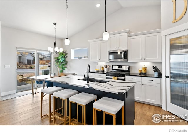 kitchen featuring a kitchen breakfast bar, appliances with stainless steel finishes, light wood-style floors, and a sink