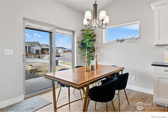 dining space with light wood-style flooring, baseboards, and a chandelier