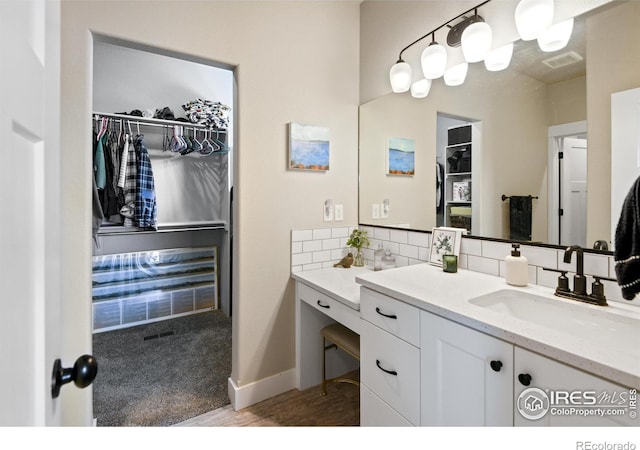 bathroom featuring tasteful backsplash, visible vents, a spacious closet, wood finished floors, and vanity