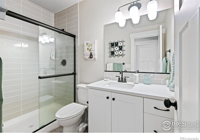 full bathroom with vanity, a shower stall, and toilet