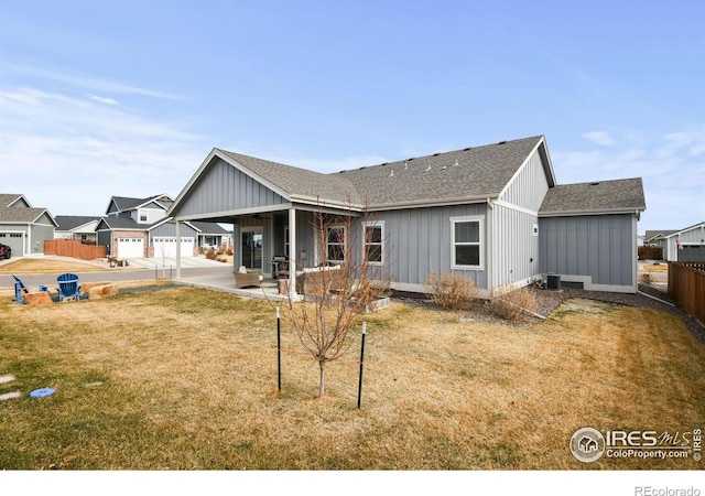 back of property featuring fence, roof with shingles, central air condition unit, a lawn, and board and batten siding