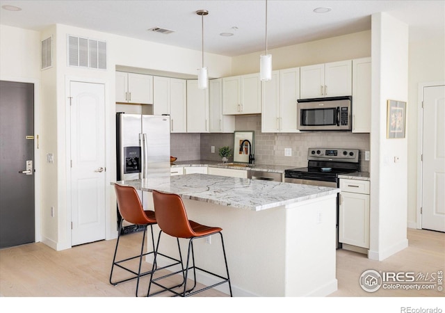 kitchen with visible vents, backsplash, appliances with stainless steel finishes, and a center island