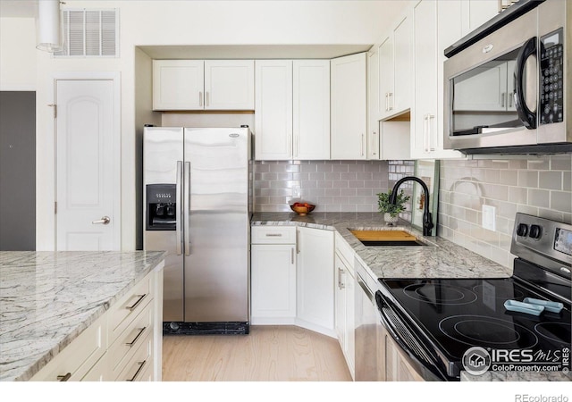 kitchen featuring visible vents, tasteful backsplash, light wood-style floors, appliances with stainless steel finishes, and white cabinets