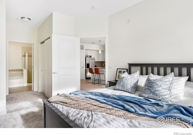 carpeted bedroom with stainless steel fridge and ensuite bathroom